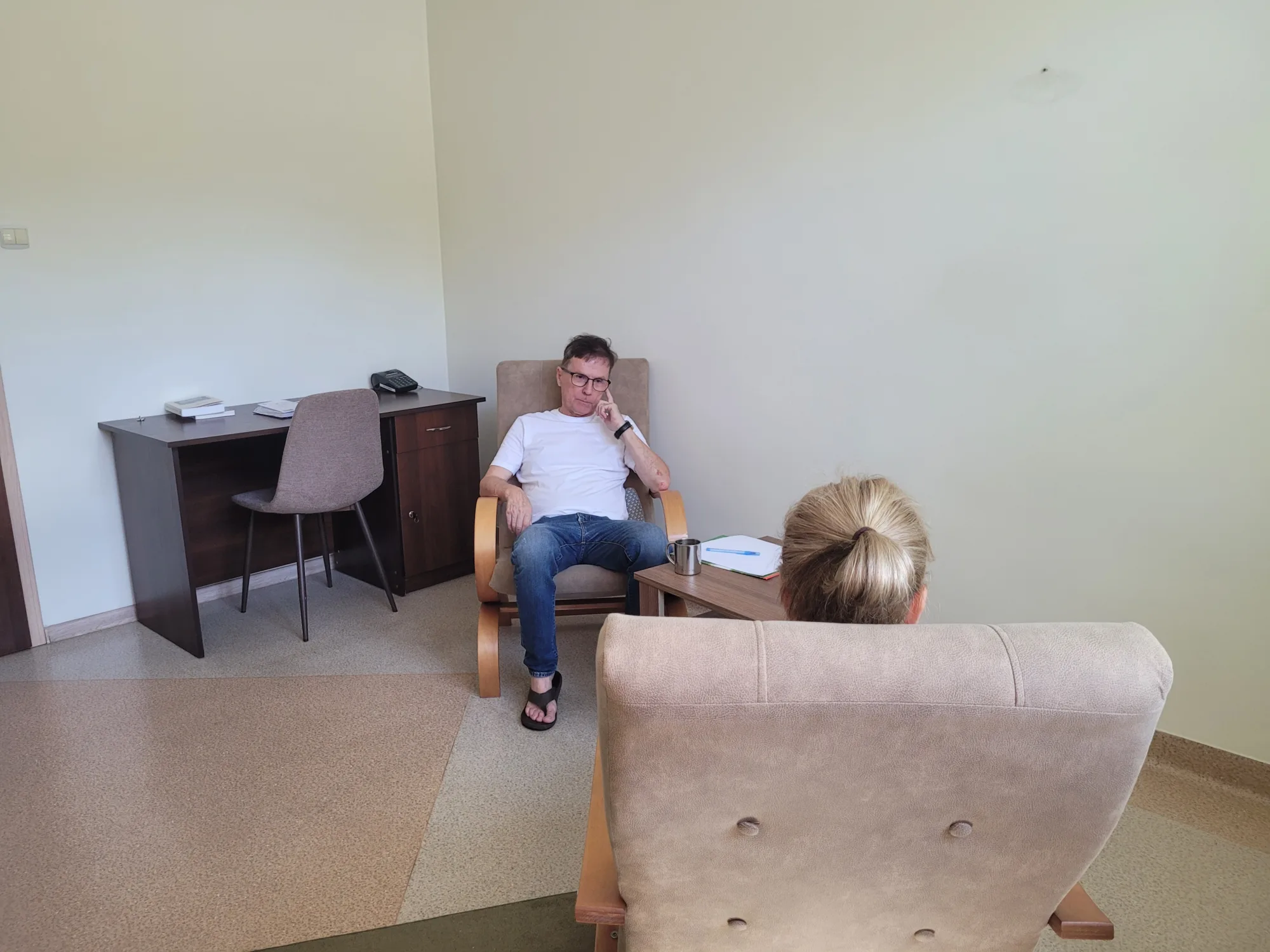 Sesja psychoterapii: terapeuta siedzi naprzeciw osoby zwróconej tyłem do obiektywu